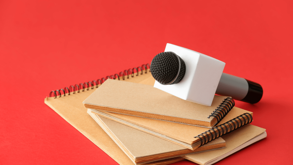 A microphone that is sitting on top of several spiral reporters notebooks.